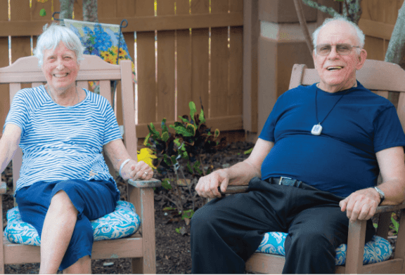 two older women sitting in chairs in a backyard