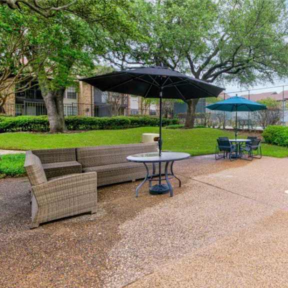 A pool with a table and chairs and umbrella in the foreground with apartment buildings in the background.