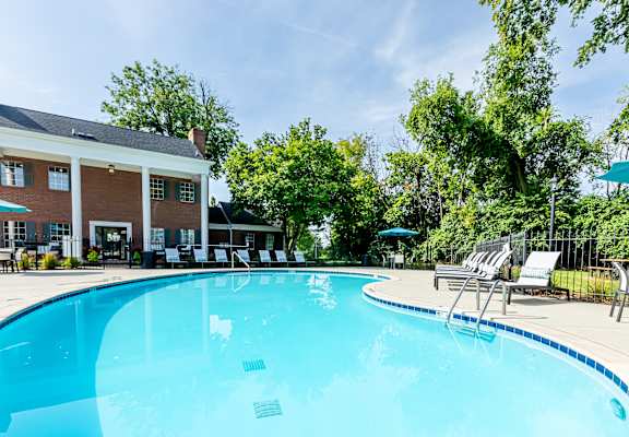 our resort style swimming pool is surrounded by chairs and umbrellas