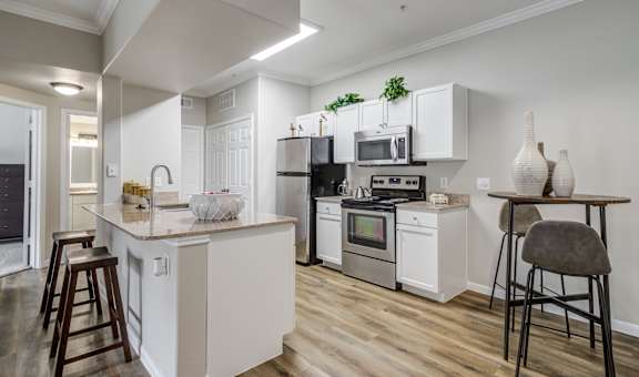 a kitchen with white cabinets and appliances and a bar with stools