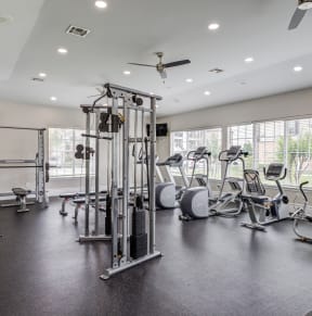 a gym with cardio machines and weights in a building with large windows