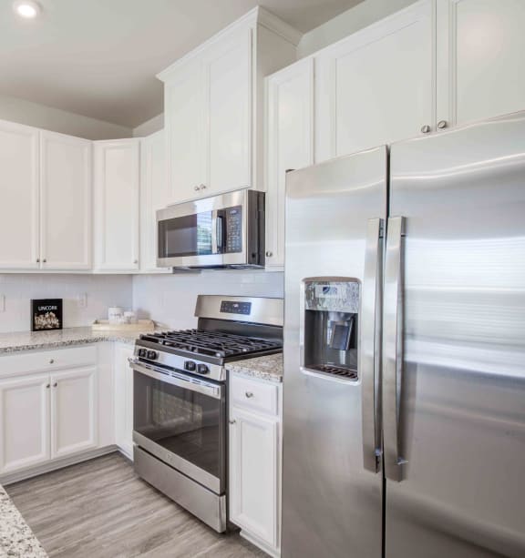 a white kitchen with stainless steel appliances and granite counter tops