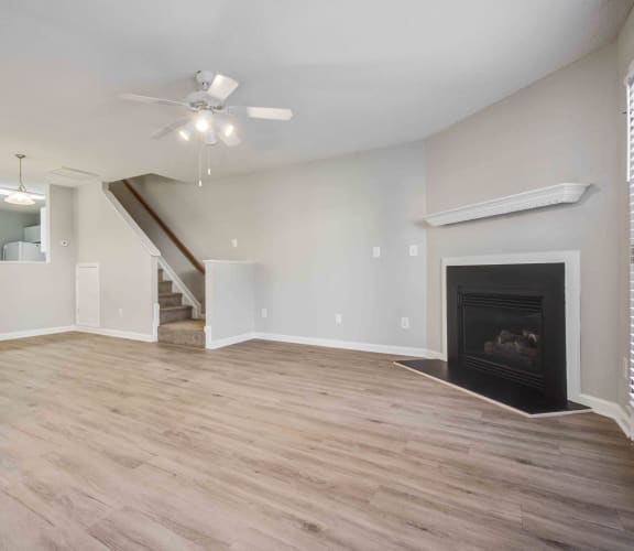 an empty living room with a fireplace and a ceiling fan