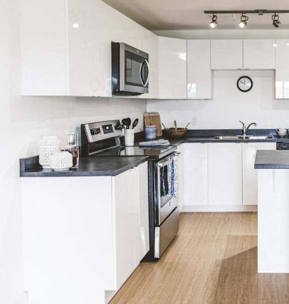A modern kitchen with a stainless steel refrigerator and wooden flooring.