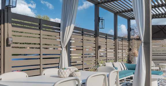 a patio with white tables and chairs and a privacy fence