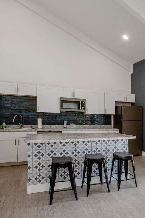 A kitchen with a white countertop and black bar stools.