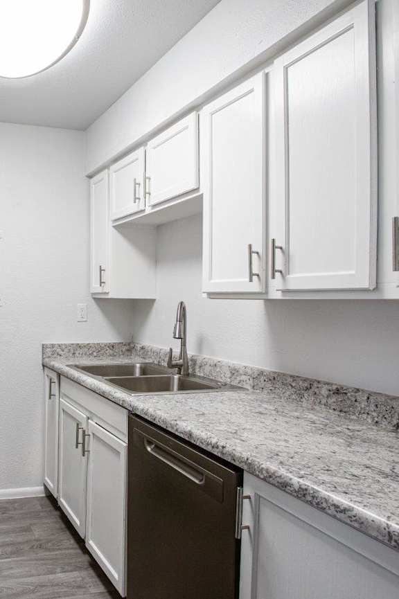 A kitchen with white cabinets and a granite countertop.