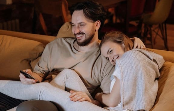 a man and woman sitting on a couch laughing