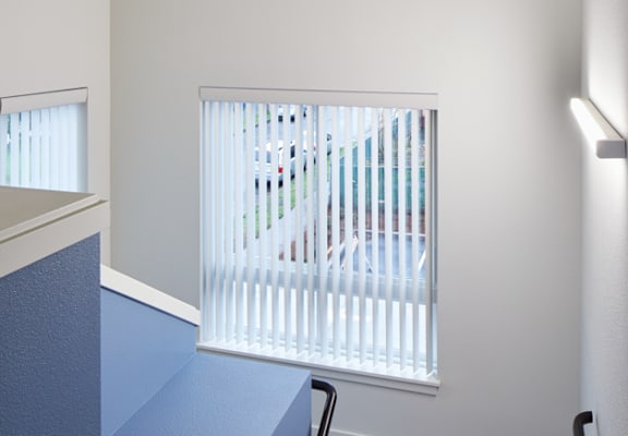 A room with a window covered by white blinds.