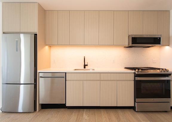 A modern kitchen with a refrigerator, dishwasher, oven, and microwave.