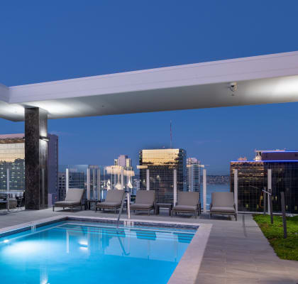 a pool on the roof of a building with a city skyline in the background
