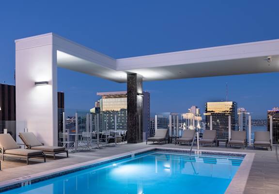 a pool on the roof of a building with a city skyline in the background
