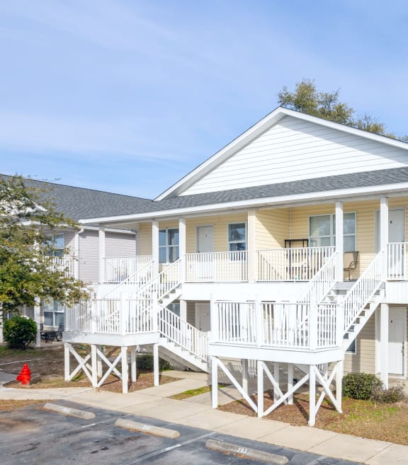 the exterior of a yellow house with stairs and a red fire hydrant