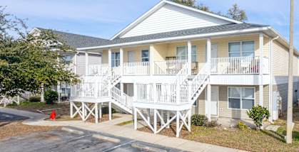 the exterior of a yellow house with stairs and a red fire hydrant