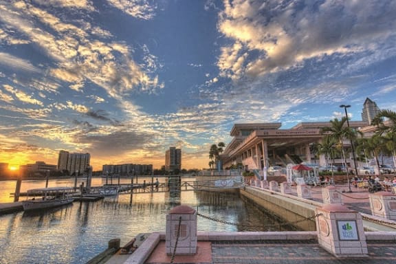 the sun is setting over the water at a marina