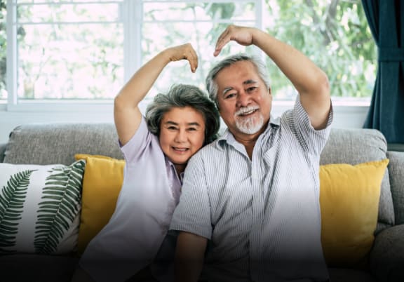 a man and a woman sitting on a couch with their arms up representing love where you live