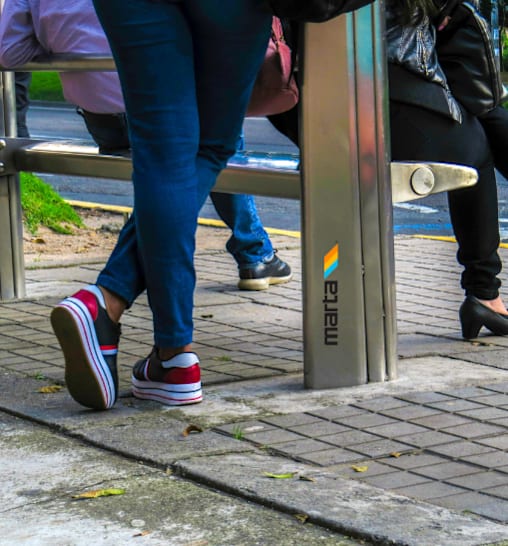 A person wearing black shoes is standing on a sidewalk.