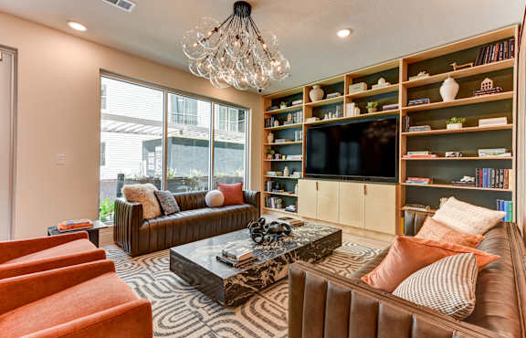 A living room with a brown couch, a coffee table, and a bookshelf.