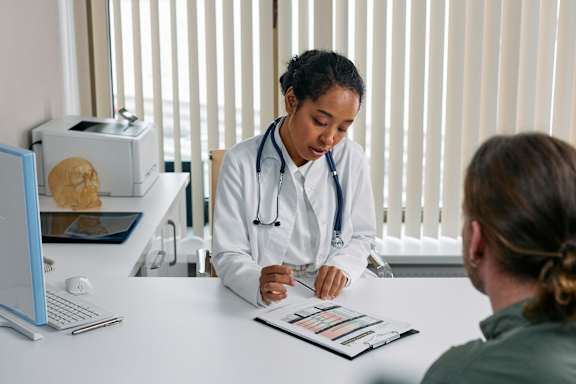 A doctor is consulting with a patient in a brightly lit room.