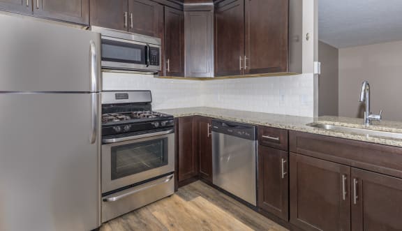 a kitchen with dark wood cabinets and stainless steel appliances