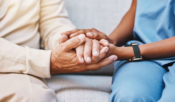 an elderly patient holding a young patients hand