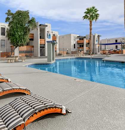 a pool with lounge chairs at the resort on a sunny day