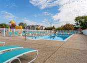 Thumbnail 2 of 6 - A sunny day at the pool with blue water and white lounge chairs.