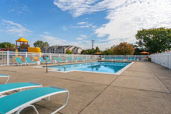 A sunny day at the pool with blue water and white lounge chairs.