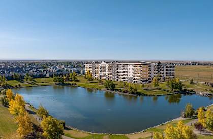 A large building is situated next to a body of water with a grassy area in front of it.