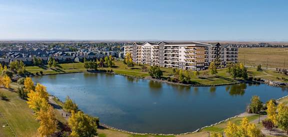 A large building is situated next to a body of water with a grassy area in front of it.