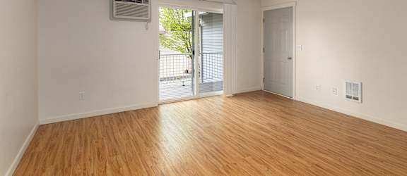 an empty living room with wood floors and a door to a balcony