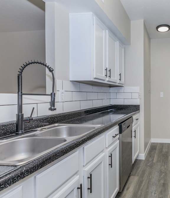 A kitchen with white cabinets and black countertops.