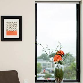 A brown chair sits next to a table with a vase of flowers on it.