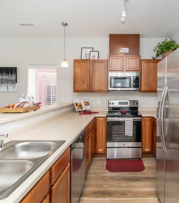 A kitchen with a refrigerator, sink, and microwave.
