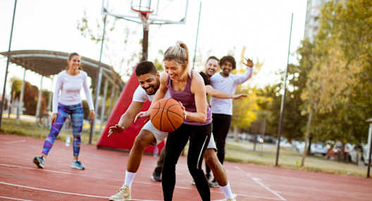 A group of people playing basketball on an outdoor court.