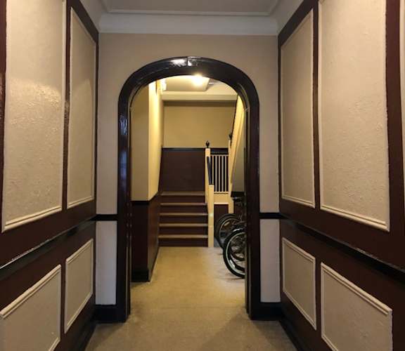 A mirror reflects a bedroom with a bed and a window.