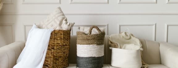 a white couch with three woven baskets on the back of it