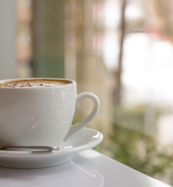 a cup of coffee on a table next to a window at The Madison, Columbus, OH, 43215