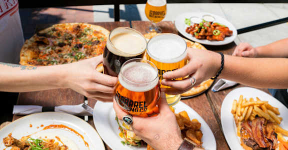 a group of people sitting at a table drinking beer and eating food