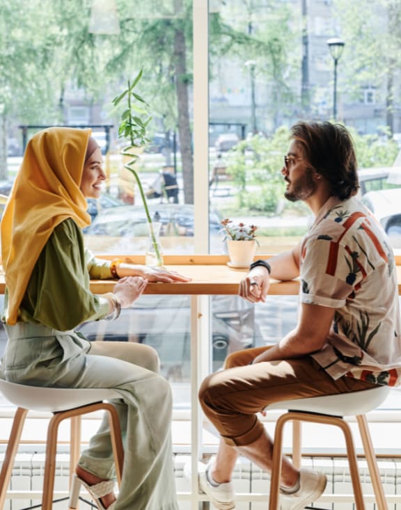 two people sitting at a table in a coffee shop