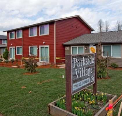 A sign that says Parkside Village stands in front of a building.