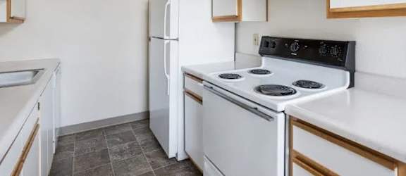 A kitchen with white appliances and wooden cabinets.