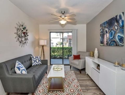 A living room with a grey couch, a coffee table, and a painting on the wall. at Reflections at Red Mountain Apartments, Arizona