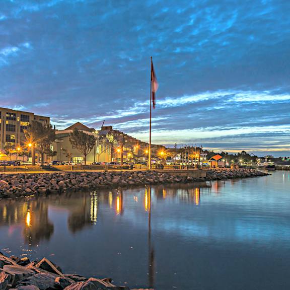 A flag is flying on a pole in front of a body of water.