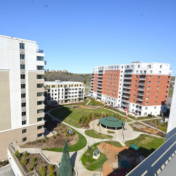 A view of a courtyard with a green roof and a white building with red balconies in the background.