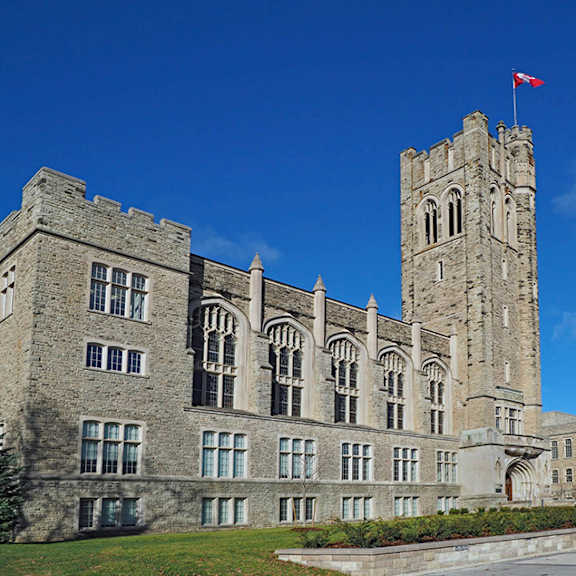 A large stone building with a tall tower and a flag on top.