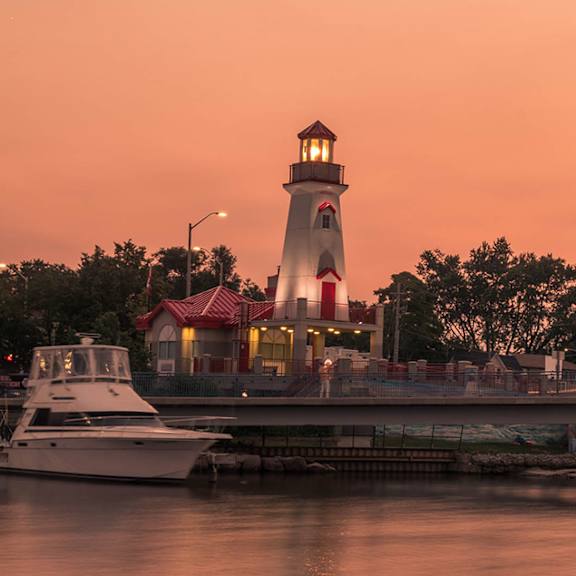 A boat is docked in front of a lighthouse.