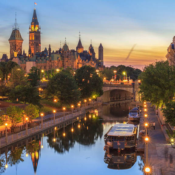 A beautiful cityscape with a clock tower and a river with boats.