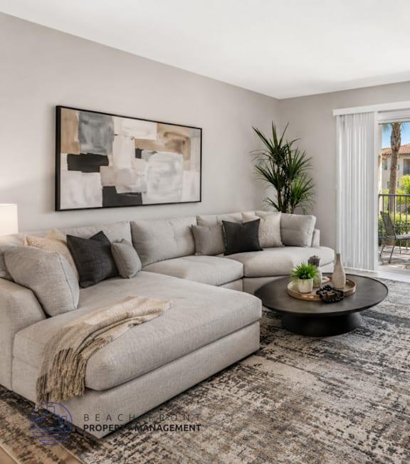 A living room with a grey couch, a coffee table, and a flat screen TV.