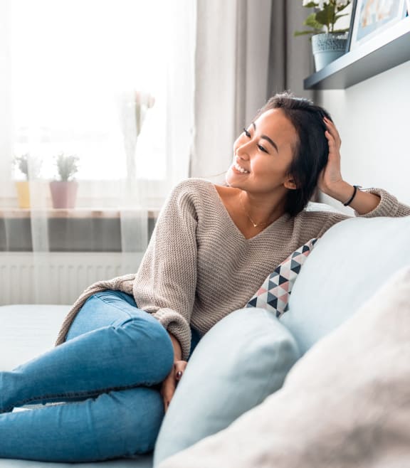 a woman sitting on a couch with her hand on her head at Aura Vegas Apartments in Las Vegas, NV